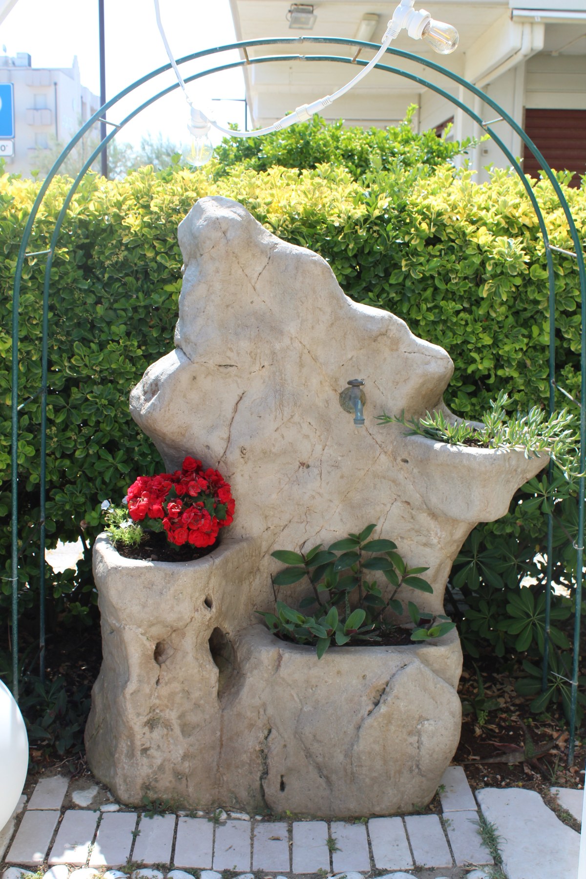 Fontana di pietra con fiori nel dehors de La Nave