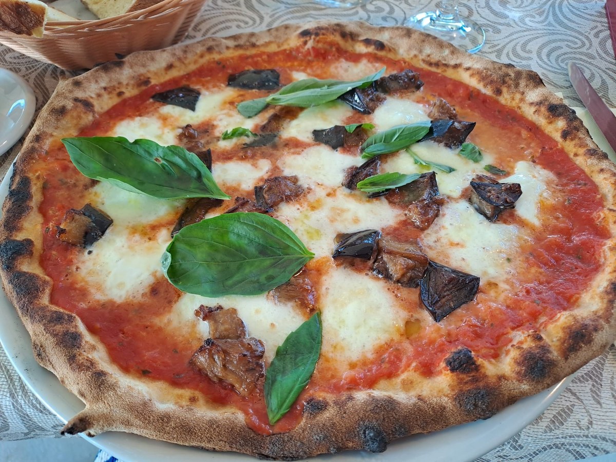 Pizza cotta in forno a legna con pomodoro, mozzarella, melanzane e basilico